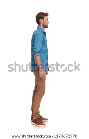 side view of a young casual man standing on white background, full body picture 