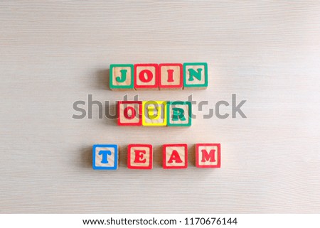 Join our team text on wooden abc cube at wood background. Business or education concept.