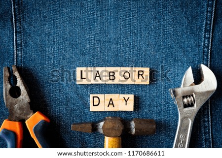 USA Labor day concept, First Monday in September. Different kinds on wrenches, handy tools, America flag and wooden tag on blue jeans background.