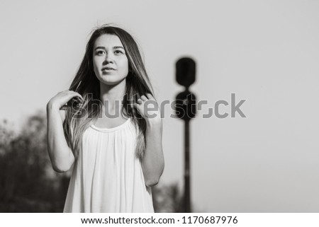 Portrait of a beautiful girl in a dress on the background of a railway lantern. Horizontally framed shot.