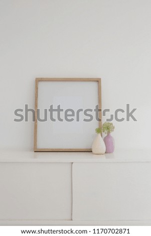 Close-up of vase and blank picture frame on table