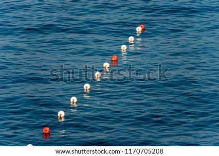 A row of orange and white buoys on the surface of the water, Mediterranean sea, Italy