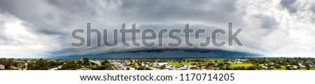Panorama Top view Aerial photo from flying drone. Dark sky and dramatic black cloud before rain.rainy storm over rice fields and over town  Sisaket province Thailand.
