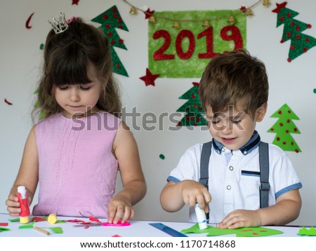 Cute kids are engaged in creativity. Smiling funny children make christmas cards. Christmas and 2019 New Year concept.