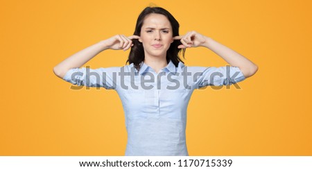 long-haired beautiful young brunette woman covering her ears with her hands