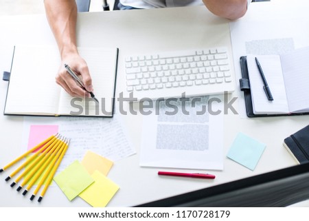 Businessman working writing business plan document and graphic designer with computer in office.