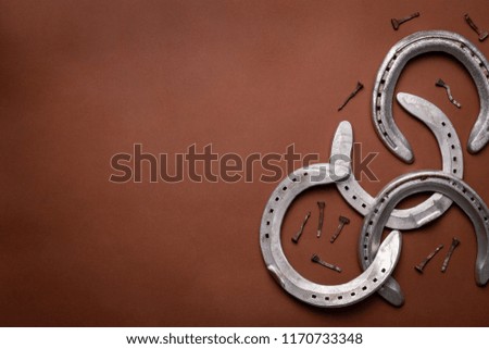 Pile of horseshoes and nails isolated on a brown background with copy space