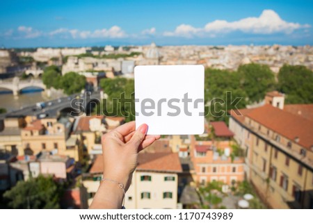 Person holding blank white paper in front of city