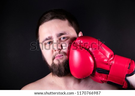Boxer in red gloves for boxing strikes the opponent to the man. A man with beard is beaten in the face with his fist. Pain from the impact.