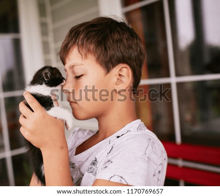 Little boy holds black and white kitty on his shoulder