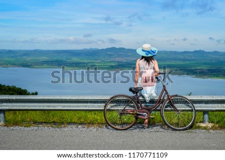 woman traveler sitting beside bicycle  on vacation background is mountain the lake.young lady tourist enjoying for nature on holiday