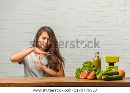 Concept of diet. Portrait of a healthy young latin woman tired and bored, making a timeout gesture, needs to stop because of work stress, time concept