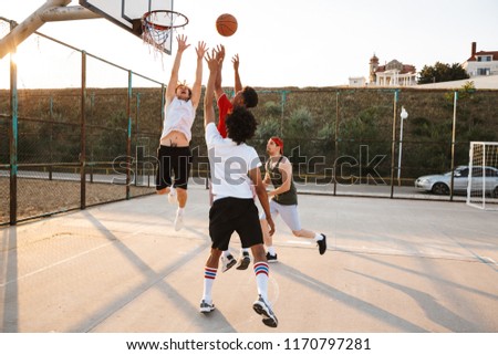 Group of young excited multiethnic men basketball players playing basketball at the sport ground