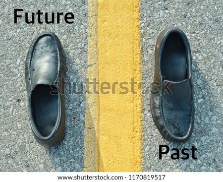 Past and future text on asphalt road. Empty shoes on road, one facing back, one facing forward with yellow line between shoes