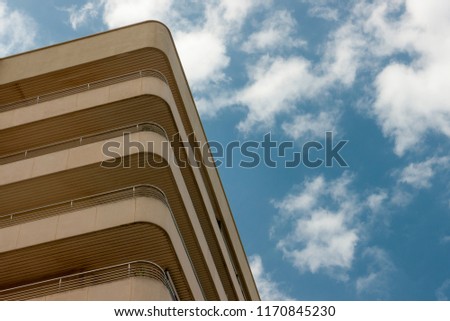 Partial low angle view of apartment building over blue sky with clouds