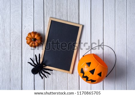 halloween background with Pumpkins, black spider and empty chalkboard on white wooden floor. Top view
