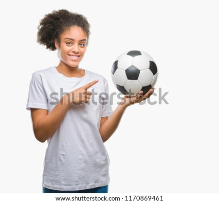 Young beautiful afro american holding soccer football ball over isolated background very happy pointing with hand and finger
