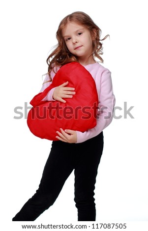 Caucasian lovely little girl hugging a large toy bright red heart symbol isolated on white background