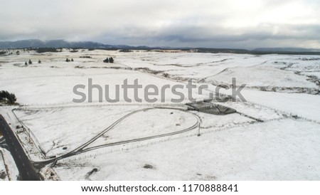 Aerial View Over Snowy Field and Road in New Zealand. Aerial drone view of road in idyllic winter landscape. Street running through the nature from a birds eye view.