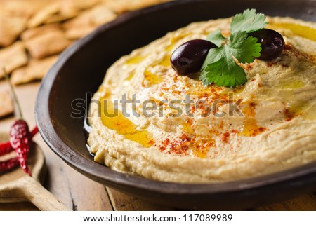 A bowl of creamy hummus with olive oil and pita chips. Royalty-Free Stock Photo #117089989