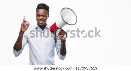Young african american man holding megaphone surprised with an idea or question pointing finger with happy face, number one