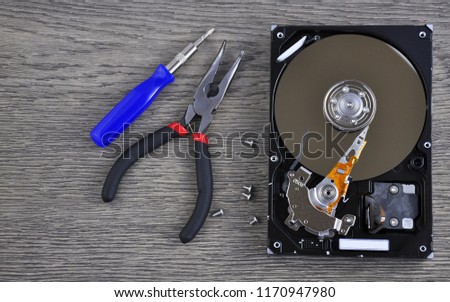 Hard drive and repair tool on wooden table close up 