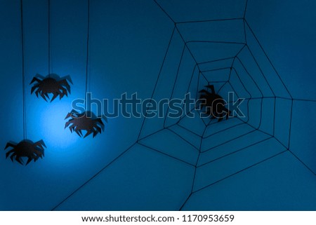 Black paper spider with web on dark blue background. Halloween concept. Paper cut style. Top view