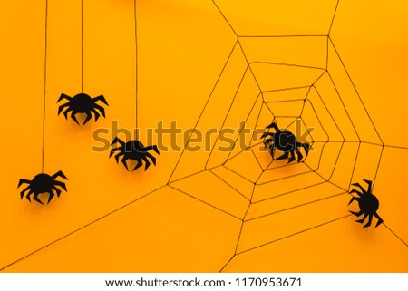 Black paper spider with web on yellow background. Halloween concept. Paper cut style. Top view