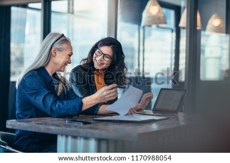 Smiling business woman working together on contract documents. Happy coworkers meeting for new project planning in office. Royalty-Free Stock Photo #1170988054