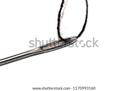 Ear of needle and black thread close up isolated