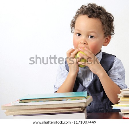 little boy eating an apple with school books on a table reel people with white background stock image and stock photo