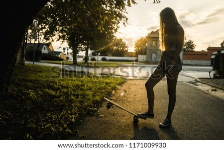 Beautiful young girl riding longboard in sunny weather
