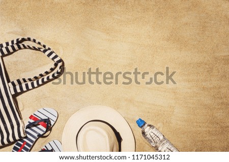 Top view of sandy beach and summer accessories. Background with copy space and visible sand texture. Border composition with copy space