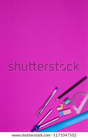A photo of stationery set: pen, rubber, sharpener, compass, protractor, ruler, crumpled paper ball and etc. on the pink background on the table . Workspace of student or office worker.