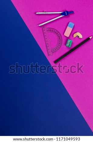 A photo of stationery set: pencil, rubber, sharpener, compass, protractor, ruler, crumpled paper ball and etc. on the pink and blue background on the table . Workspace of student or office worker.