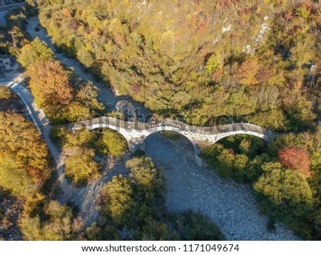 Aerial view of old Kalogeriko triple arched stone bridge on Vikos canyon, Zagorohoria, Greece, Europe