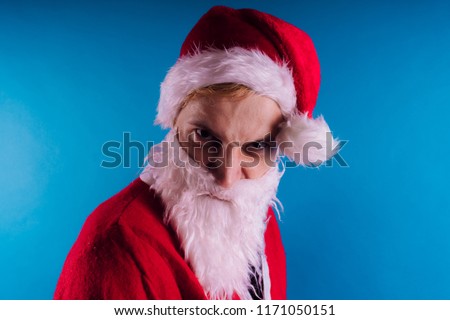 Emotional Santa Claus on a blue background. The concept of bad Santa Claus. Happy New Year and merry Christmas!
