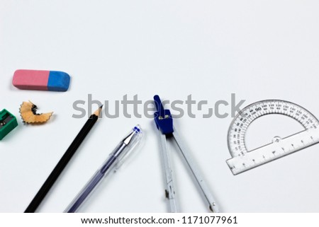 A close-up photo of stationary set: pen, pencil, compass, rubber, protractor and etc. on the white background on the table in office, school or university. A workspace of student or an office worker.