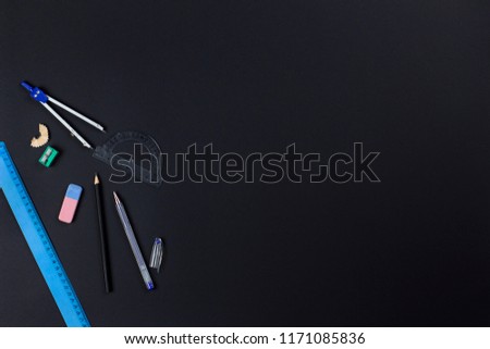 A photo of stationery set: pencil, rubber, sharpener, compass, protractor, ruler and crumpled paper ball on the pink background on the table . Workspace of student or office worker.