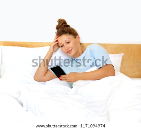 Woman relaxing on her bed/using smarthone