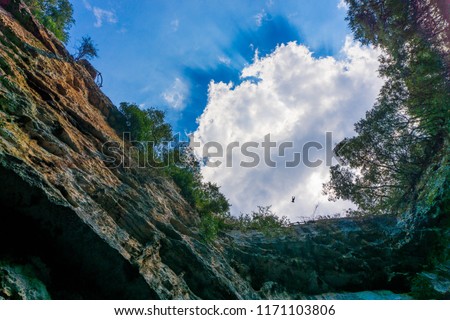 Melissani cave or Melissani lake in Kefalonia Greece. View of the hole of the cave's roof surrounded by trees