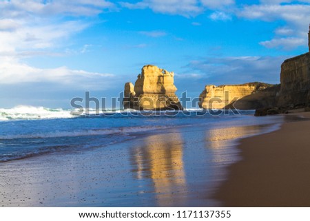 colourful image of twelve apostles at great ocean road with cliffs, cloudy sky and reflections on sand