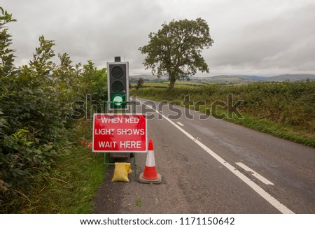 'When Red Light shows wait here' sign during roadworks on a country lane