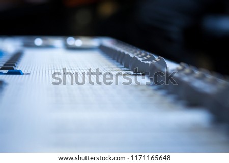 Low level view of a professional audio mixing console and digital Faders, with selective soft focus foreground and background