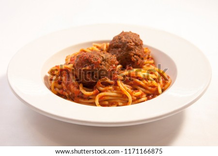 spaghetti noodles in marinara sauce topped with meatballs and in white bowl 