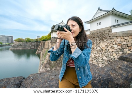 happy travel girl sitting and taking pictures of the scenary of osaka castle with a excting smile. Royalty-Free Stock Photo #1171193878
