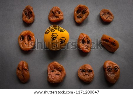 Old, shriveled apricots around one fresh. Youth against old age. Envy, malevolence. Dark background, vignetting. The picture is made by the author.