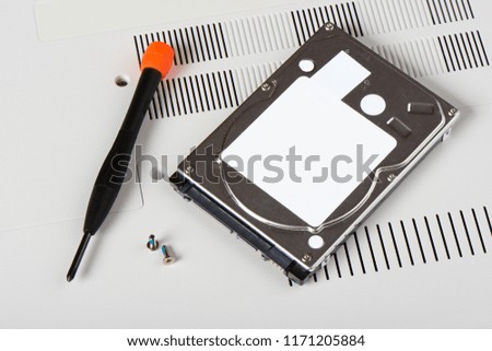 HDD(Hard Disk Driver) with screws and screwdriver on a bottom of laptop