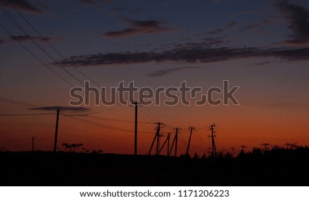 Sunset landscape with 
electric pole and silhouettes and colorful cloudy sky background.