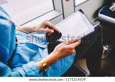 Cropped image of woman holding modern digital tablet connected to wifi inside bus  making booking online, female tapping on portable computer screen sitting in public transport browse  in networks
